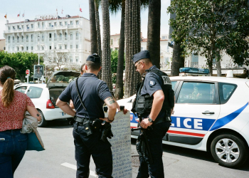 Police officers and a civilian interact near a police car on a busy city street.
