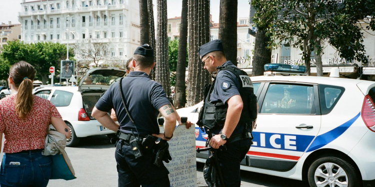 Police officers and a civilian interact near a police car on a busy city street.